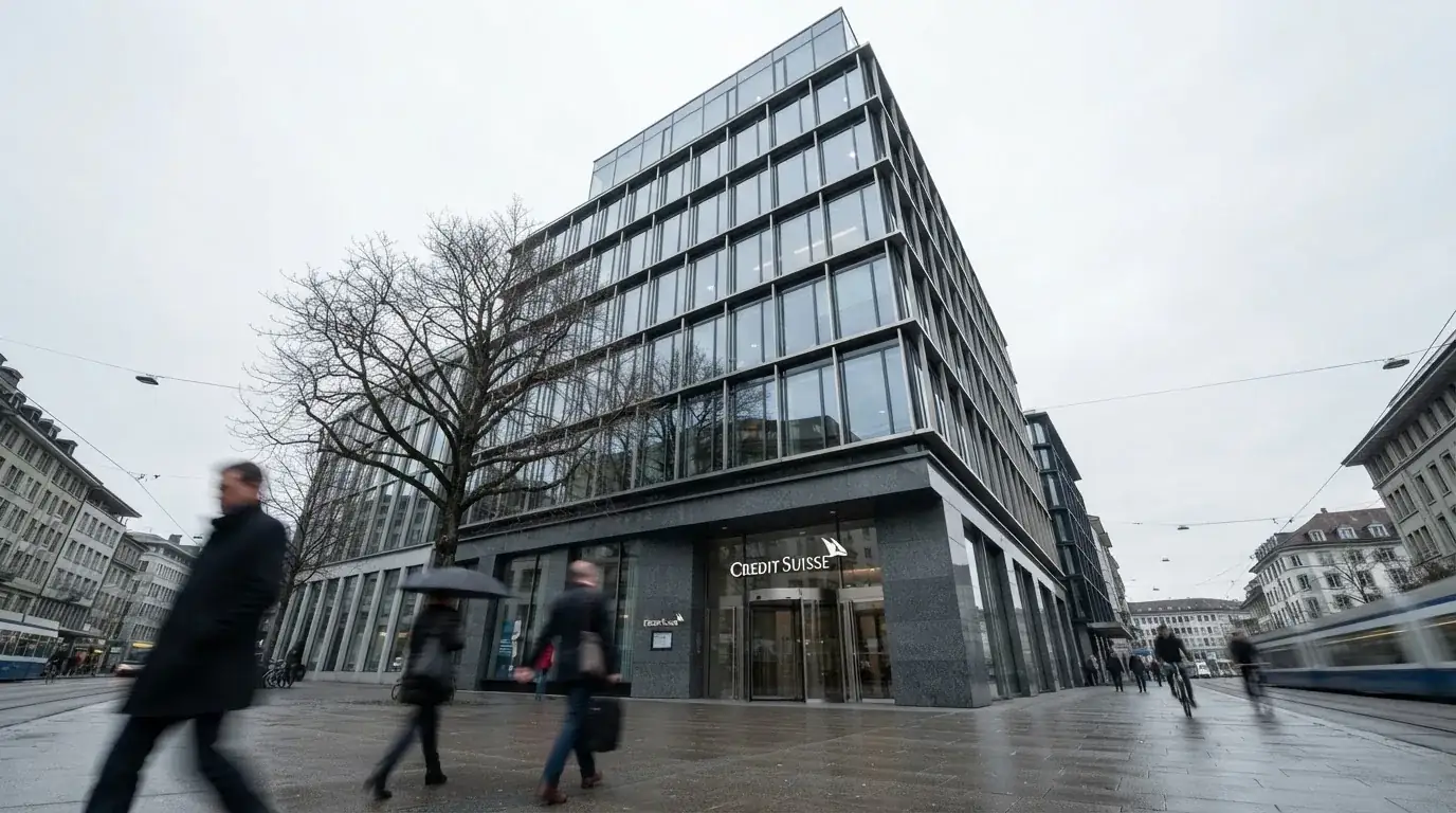 Blick auf ein Bankgebäude mit Glasfassade von der Strasse aus, Passanten gehen unscharf vorbei.